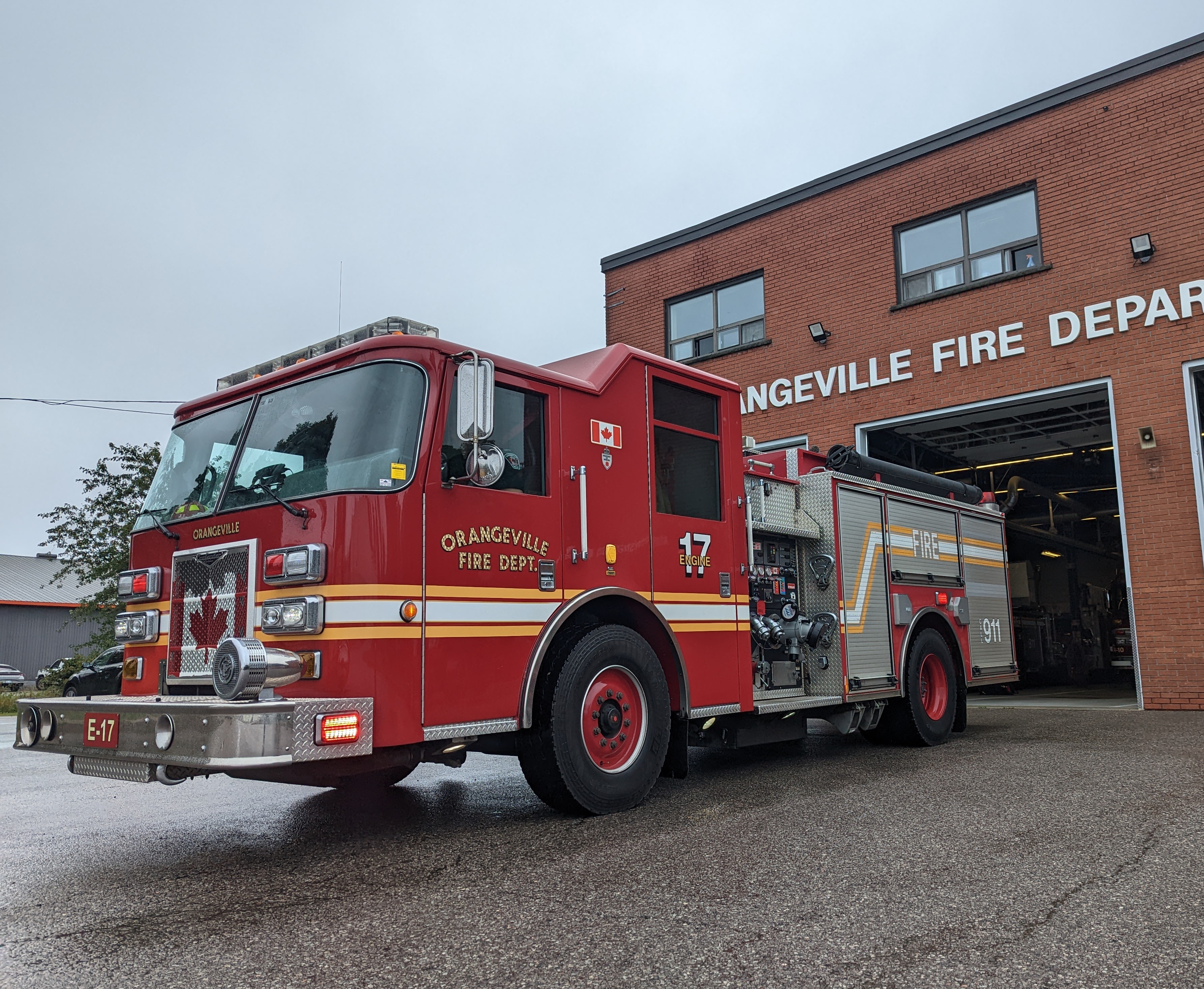 A red fire truck parked at the front of a fire station that reads Orangeville Fire Department